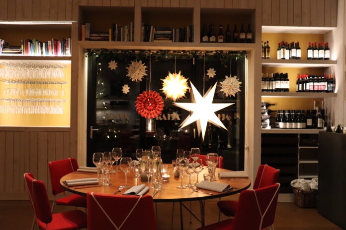Miljöbild inne på Kaija ett runt bord med sju röda stolar, ett stort fönster med julstjärnor.